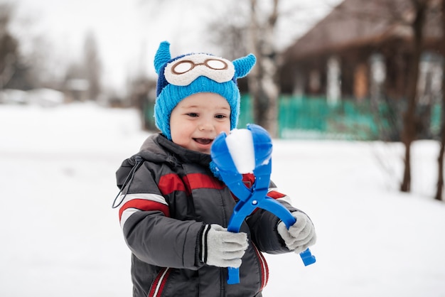 Gelukkig jongetje kind spelen sneeuwballen in de winter