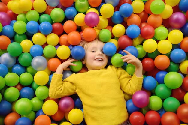 Gelukkig jongetje met plezier in de ballenbak met kleurrijke ballen.