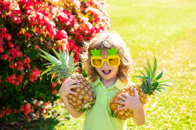 Gelukkig jongetje met t-shirt met een ananas Kinderen met tropisch fruit buiten