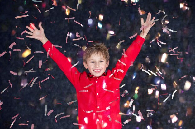 Gelukkig jongetje op vakantie Het kind verheugt zich in vliegende glimmende confetti