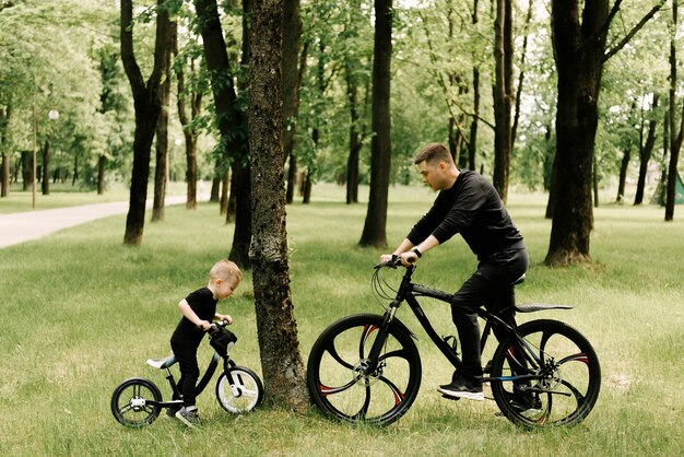 Gelukkig jongetje rijdt op een fiets met een jonge vader in het park