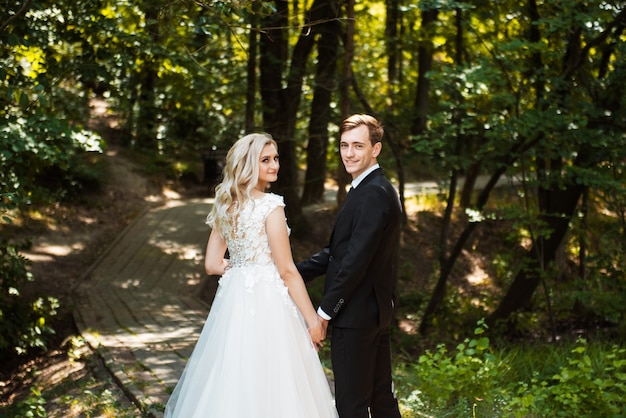 Gelukkig jonggehuwde vrouw en man omarmen in groen park. Liefdevolle bruidspaar buiten. Bruid en bruidegom. Bruid en bruidegom op trouwdag wandelen buiten op de zomer groene natuur