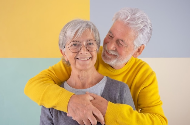 Gelukkig Kaukasisch mooi senior koppel staande over geïsoleerde kleurrijke achtergrond knuffelen met liefde Ouderen witharige mensen glimlachend zorgeloos genieten van pensioen goed gezelschap en vrije tijd