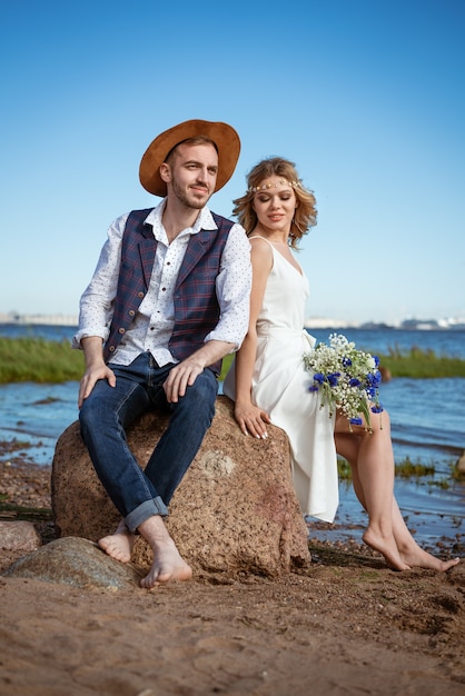 Gelukkig kaukasisch paar man en vrouw op het strand zomerdag met een boeket bloemen in haar hand