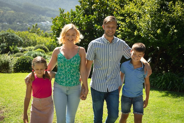 Gelukkig kaukasisch stel met dochter en zoon buiten, wandelend in de zonnige tuin. familie genieten van quality time samen.