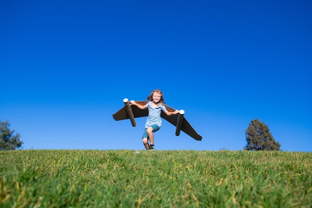 Gelukkig kind buiten spelen op groen gras en blauwe lucht Kid piloot met speelgoed jetpack Kid jongen spelen met...