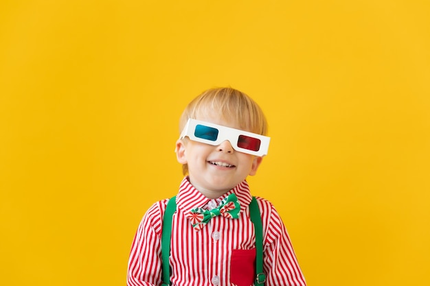 Gelukkig kind dat 3d bril draagt tegen gele muur.