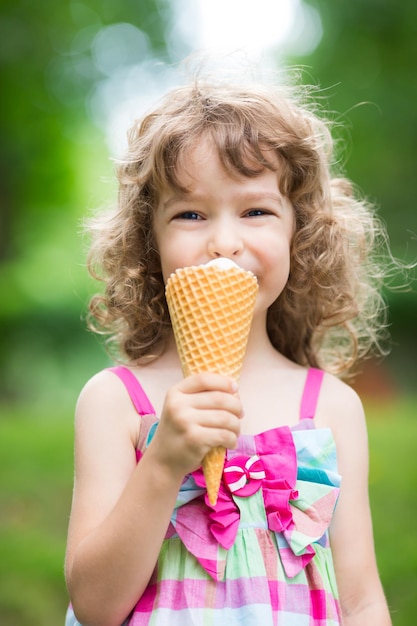 Gelukkig kind dat buiten ijs eet in het zomerpark