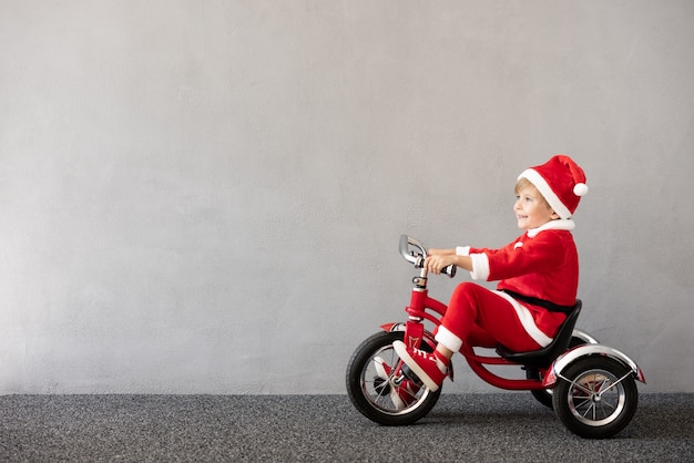 Gelukkig kind dat kerstkostuum draagt Kid rijdt op de fiets Xmas vakantieconcept