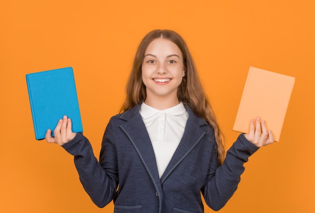 Gelukkig kind dat schoolboek op gele achtergrondwerkmap presenteert