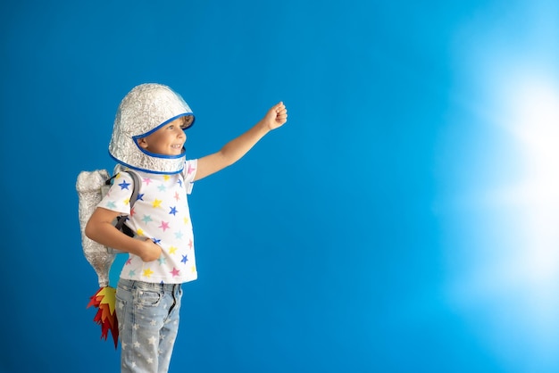 Foto gelukkig kind doet zich voor als astronaut portret van kind tegen blauwe achtergrond