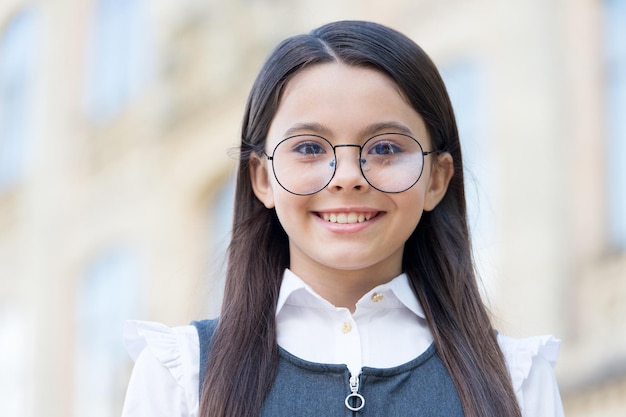 Gelukkig kind draagt een ronde bril en een formele mode-uniforme kennisdag ziet er schoolonderwijs uit