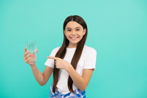 Gelukkig kind drinkt een glas water om gehydrateerd te blijven en de dagelijkse waterbalans met de vinger te houden