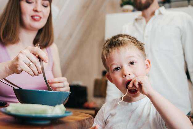 Gelukkig kind eet pasta in de keuken met haar familie