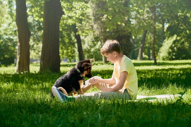 Gelukkig kind en kleine puppy spelen samen in het stadspark