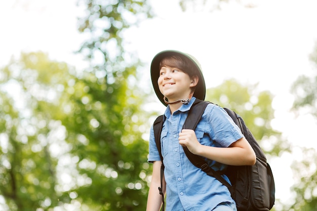 Gelukkig kind gaat wandelen met rugzak in de zomer natuur