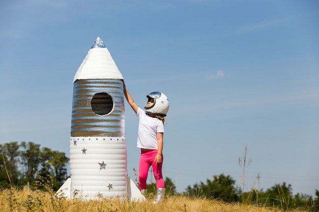 Gelukkig kind gekleed in een astronaut kostuum spelen met handgemaakte raket.