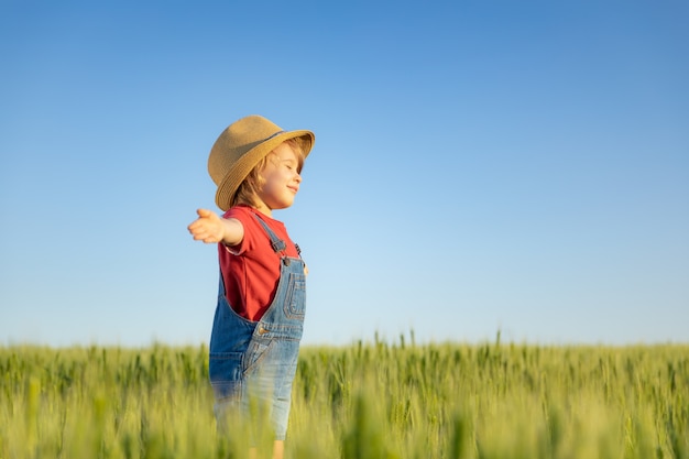 Gelukkig kind genieten van de zon buiten in een groen veld Portret van een kind tegen de zomer blauwe hemel