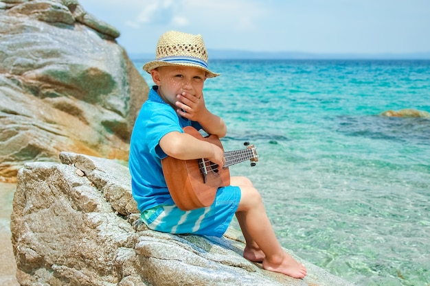 Gelukkig kind gitaarspelen door de zee griekenland op natuur achtergrond