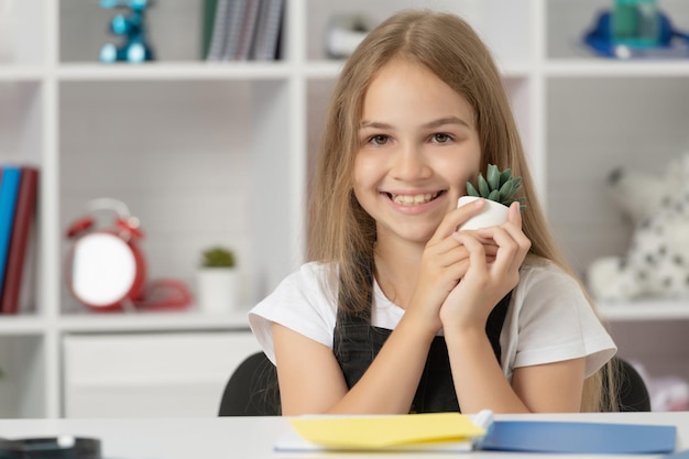 Gelukkig kind houdt potplant vast in kopieerruimte in schoolklas