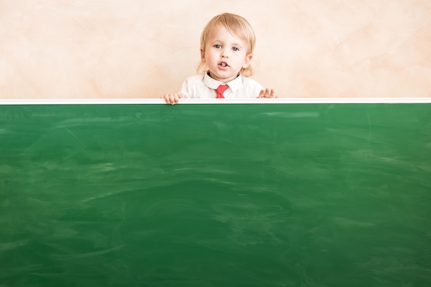 Gelukkig kind in de klas. Grappige jongen tegen schoolbord. Terug naar school. onderwijs concept