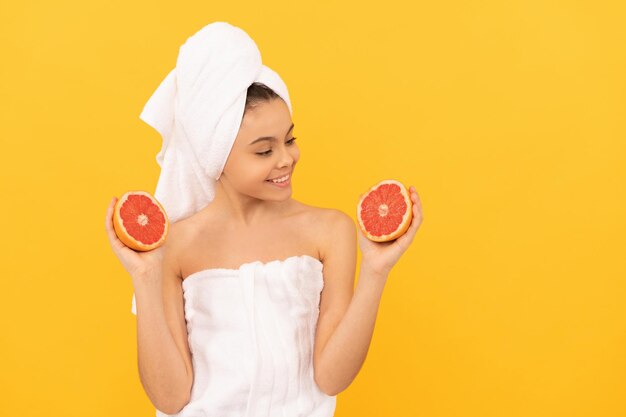 Gelukkig kind in handdoek met grapefruit op gele achtergrondexemplaarruimte