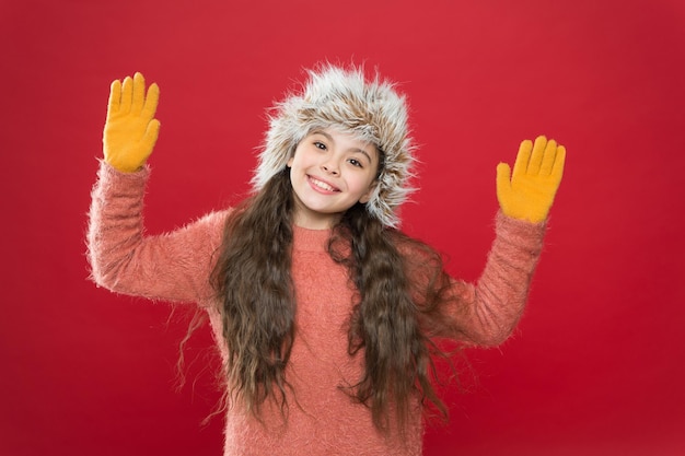 Gelukkig kind in warme winterkleren van gebreide trui en handschoenen met oorklep hoed klaar voor vakantie-activiteit, winter.