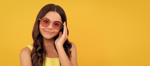 Gelukkig kind in zomer bril heeft krullend haar op gele achtergrond schoonheid kind gezicht horizontale poster tiener meisje geïsoleerde portret banner met kopie ruimte