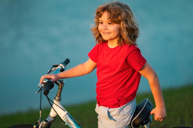 Gelukkig kind jongen fietsten in zomer park fiets droom dromerige kinderen gezicht dagdromer kind portret dichtbij