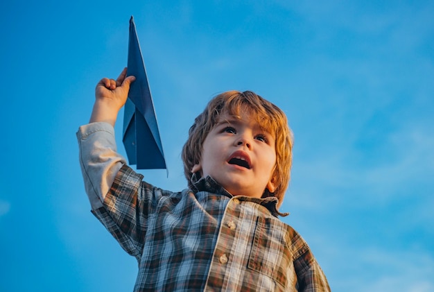 Gelukkig kind jongen loopt op weide met speelgoed vliegtuig in de zomer in de natuur kleine schattige jongen spelen met