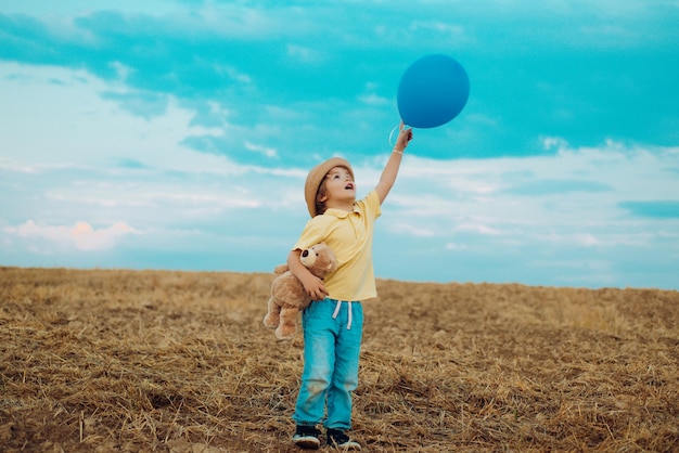 Gelukkig kind jongen met ballonnen buiten springen tegen blauwe hemelachtergrond vrijheid voor kinderen vrijheid c