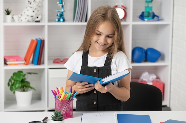 Gelukkig kind leesboek op schoolles in de klas draagt een uniforme lezer