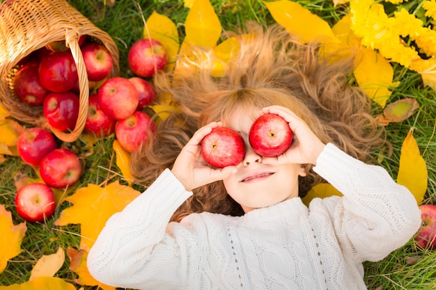 Gelukkig kind liggend op herfstbladeren. Grappig kind buiten in het herfstpark