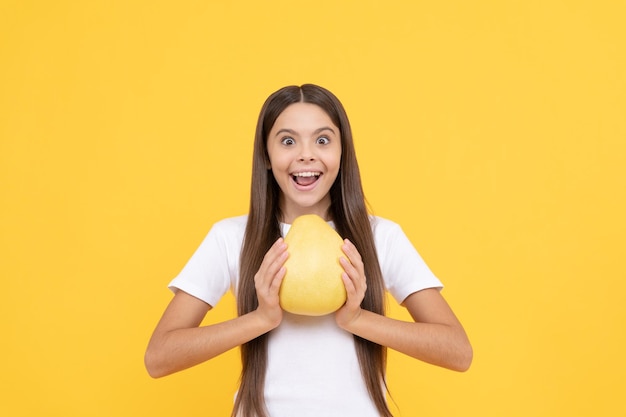 Gelukkig kind meisje houdt grote citrusvruchten van gele pummelo of pomelo vol vitamine dieet