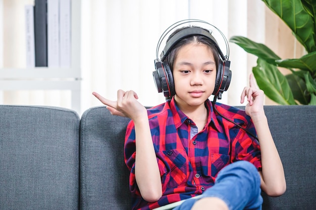 Gelukkig kind meisje luisteren naar muziek met digitale tablet zittend op de bank