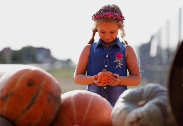 Foto gelukkig kind meisje met kleine pompoen buitenshuis.