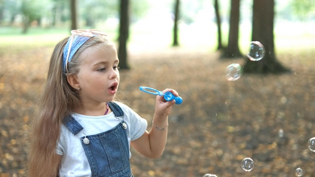 Gelukkig kind meisje zeepbellen blazen buiten in groen park Outdoor zomeractiviteiten concept