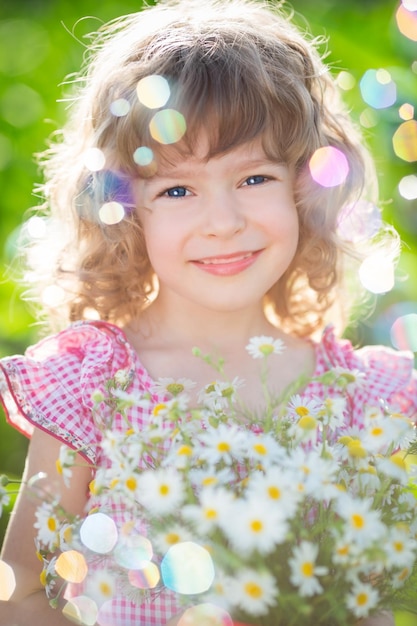 Gelukkig kind met boeket van madeliefjebloemen tegen groene achtergrond Lente familie vakantie concept Moederdag