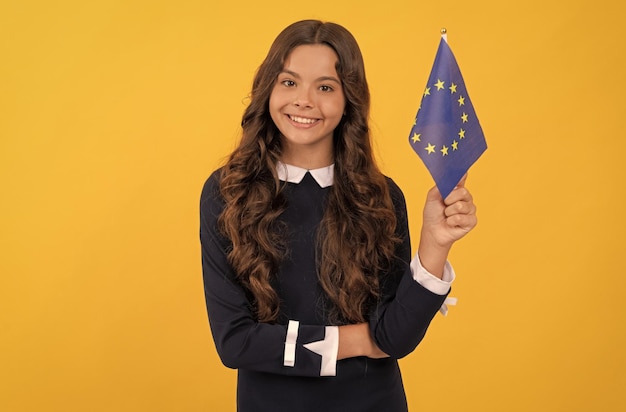 Gelukkig kind met europese unie vlag op gele achtergrond toeristisch visum in schengen land kind meisje reizen en studeren in het buitenland eurozone vakantie onderwijs in vreemde taal school