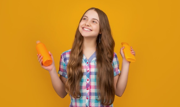 Gelukkig kind met haarconditionerfles op gele achtergrond