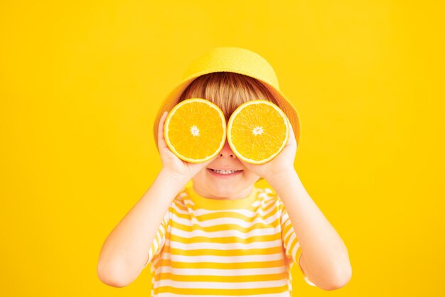 Gelukkig kind met plakjes sinaasappelfruit als een zonnebril