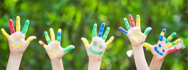 Gelukkig kind met smiley op handen tegen groene lenteachtergrond