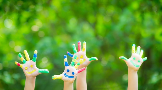 Gelukkig kind met smiley op handen tegen groene lenteachtergrond