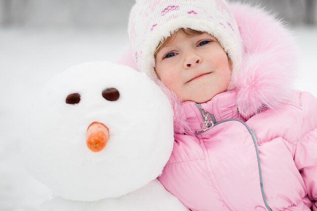 Gelukkig kind met sneeuwpop in de winter