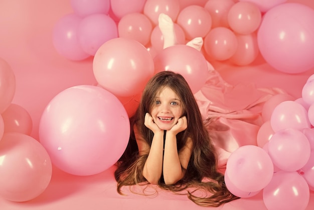 Gelukkig kind plezier jeugd meisje met ballonnen op roze achtergrond