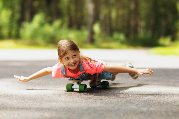 Gelukkig kind rijdt op een skateboard in het park op een zonnige Zomerochtend