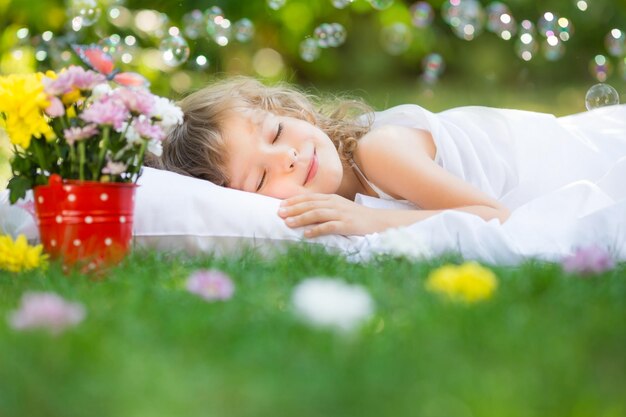 Gelukkig kind slapen op groen gras buiten in de lentetuin