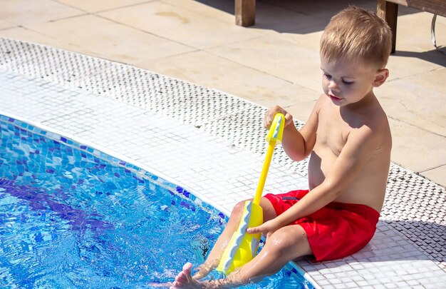 Gelukkig kind speelt in het zwembad met een waterpistool selectieve focus