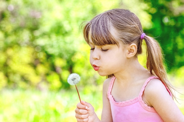 Gelukkig kind spelen en blazen paardebloem in de natuur