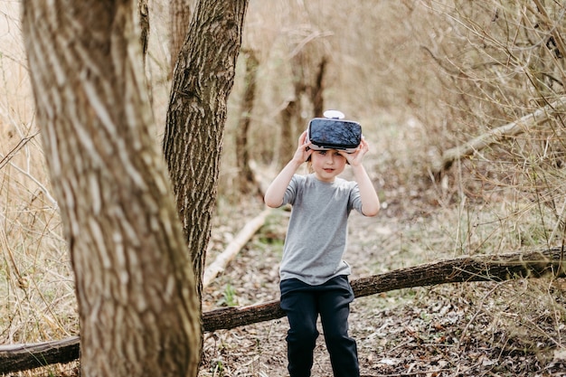 Gelukkig kind spelen en kijken naar visuele realiteitsbril of Vr-technologie op bos prachtige natuur.